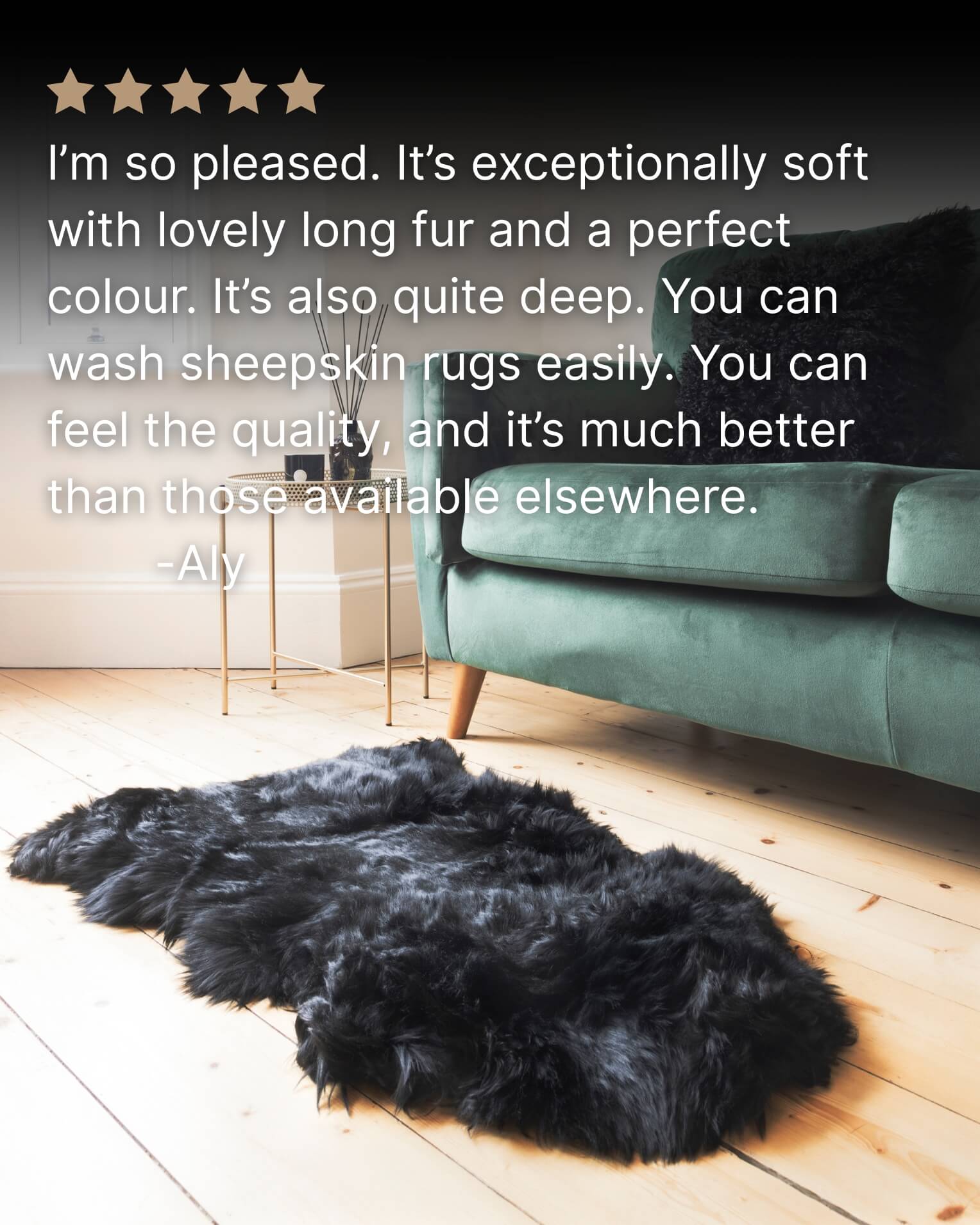 Black sheepskin rug on a wooden floor with a teal sofa in the background