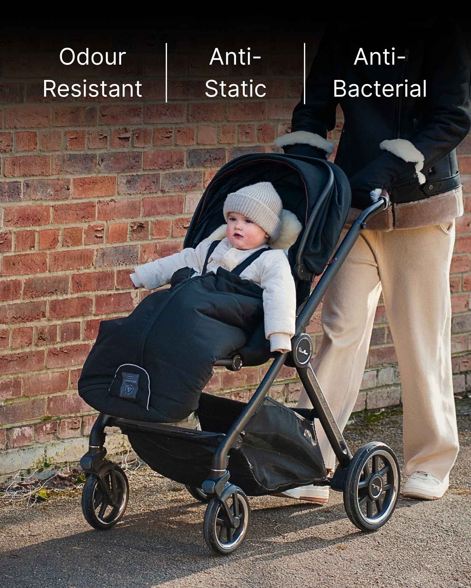 Black stroller with a baby inside a footmuff