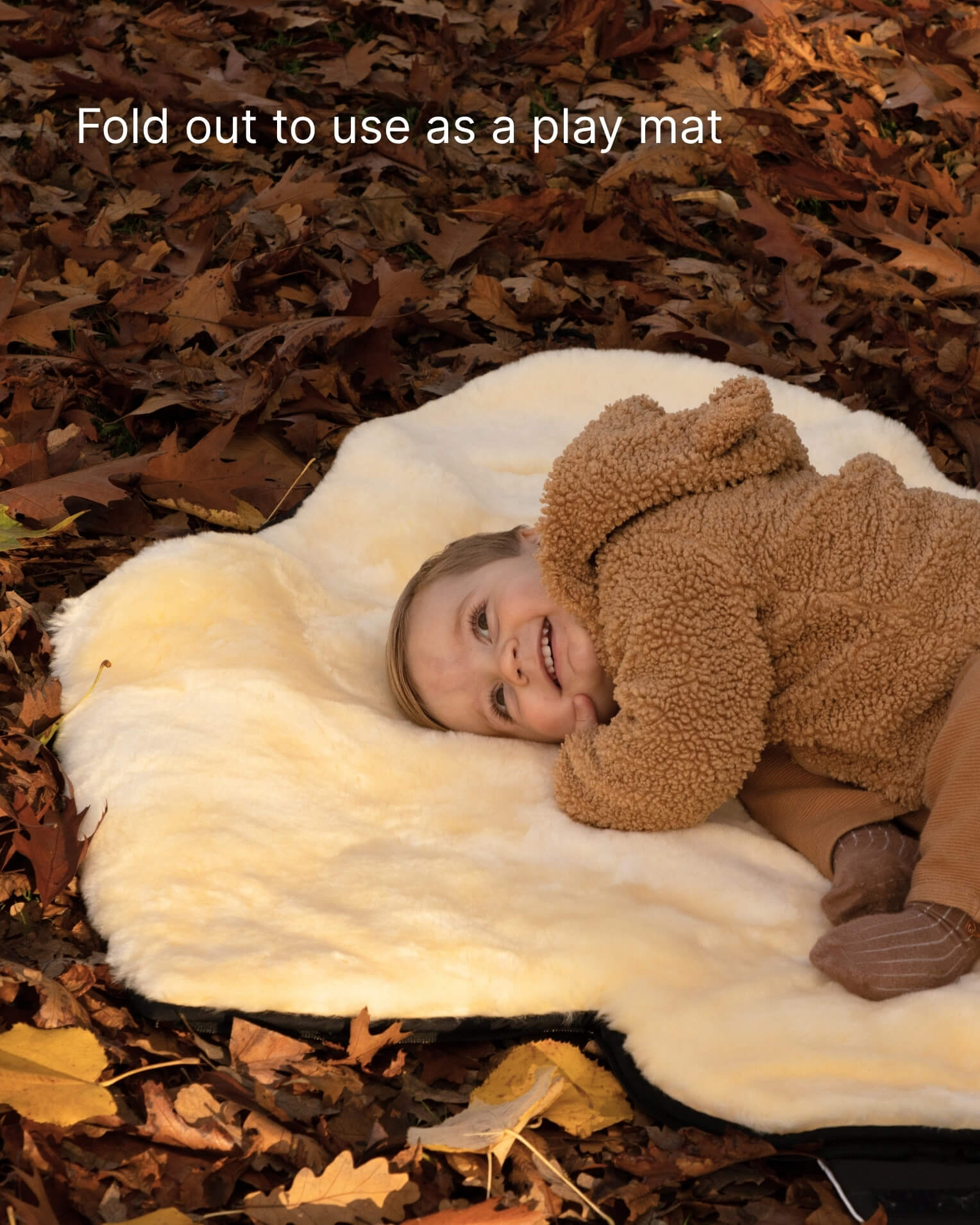 Child lying on a white footmuff opened out as playmat