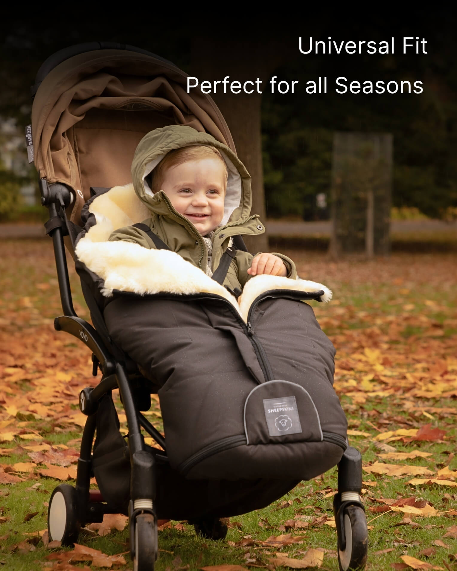 Child in a stroller with a footmuff, surrounded by autumn leaves.