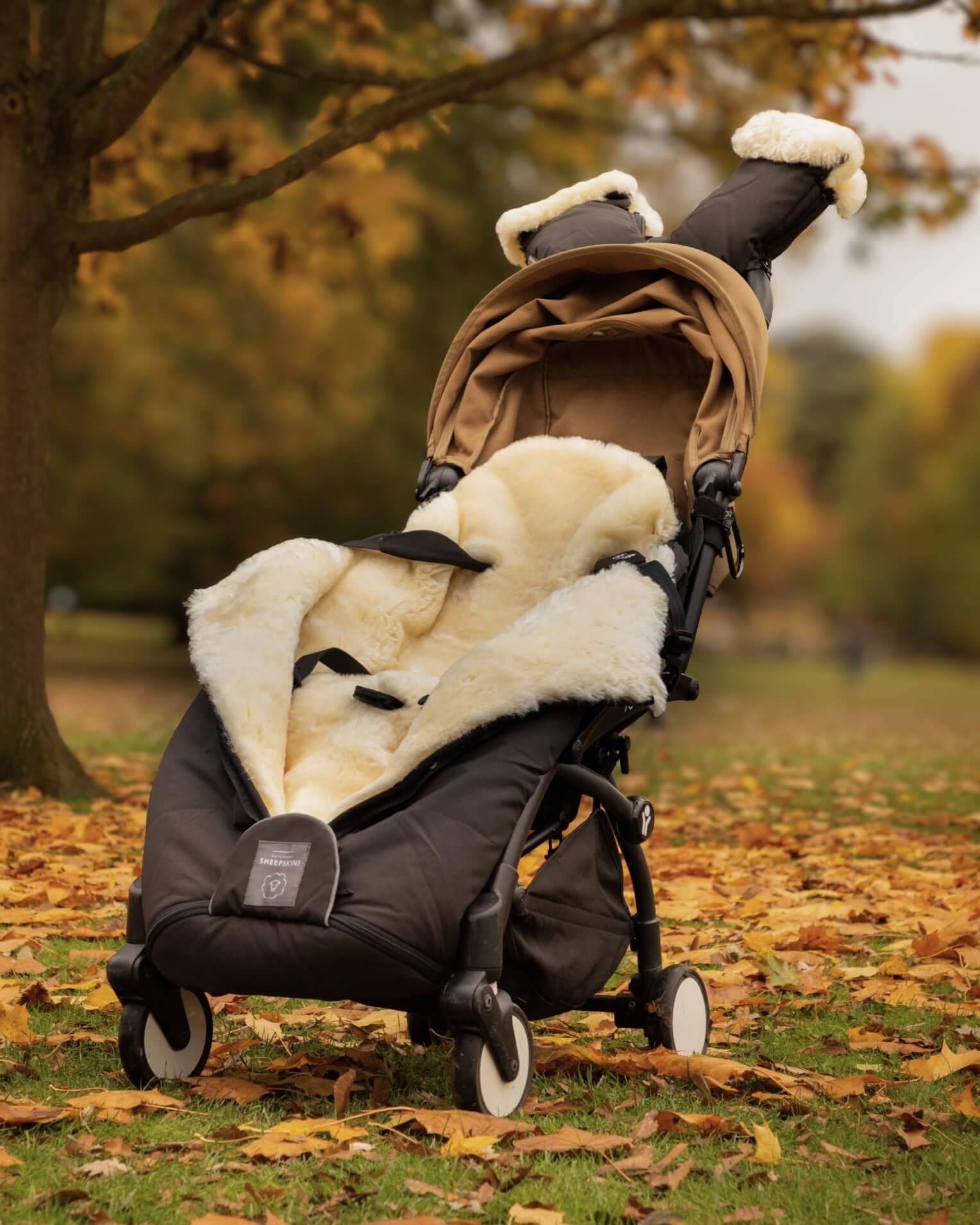 Stroller with a sheepskin-lined footmuff in an autumn park setting