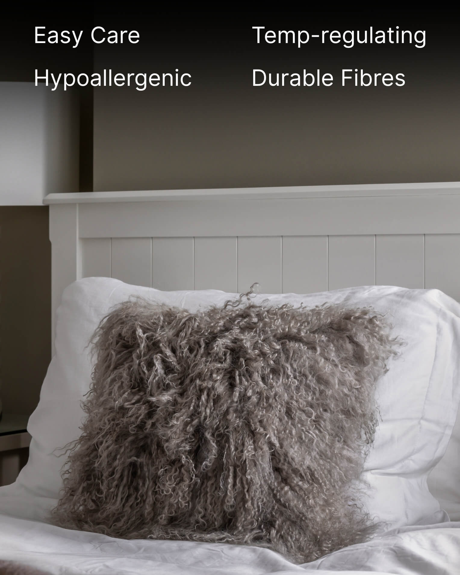 Grey mongolian sheepskin pillow on white bed