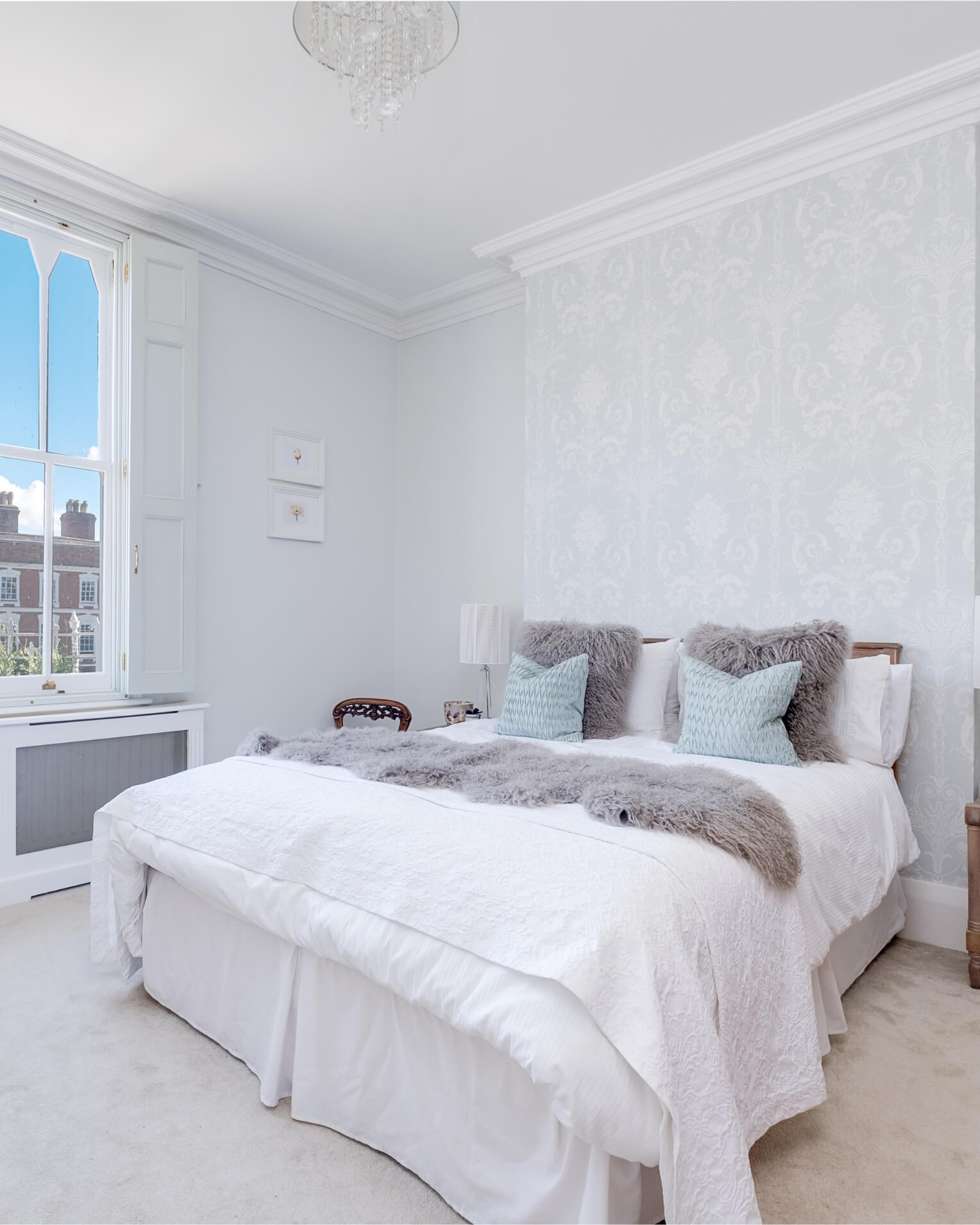 2 Grey mongolian sheepskin pillows on white bed with Grey mongolian sheepskin rug 