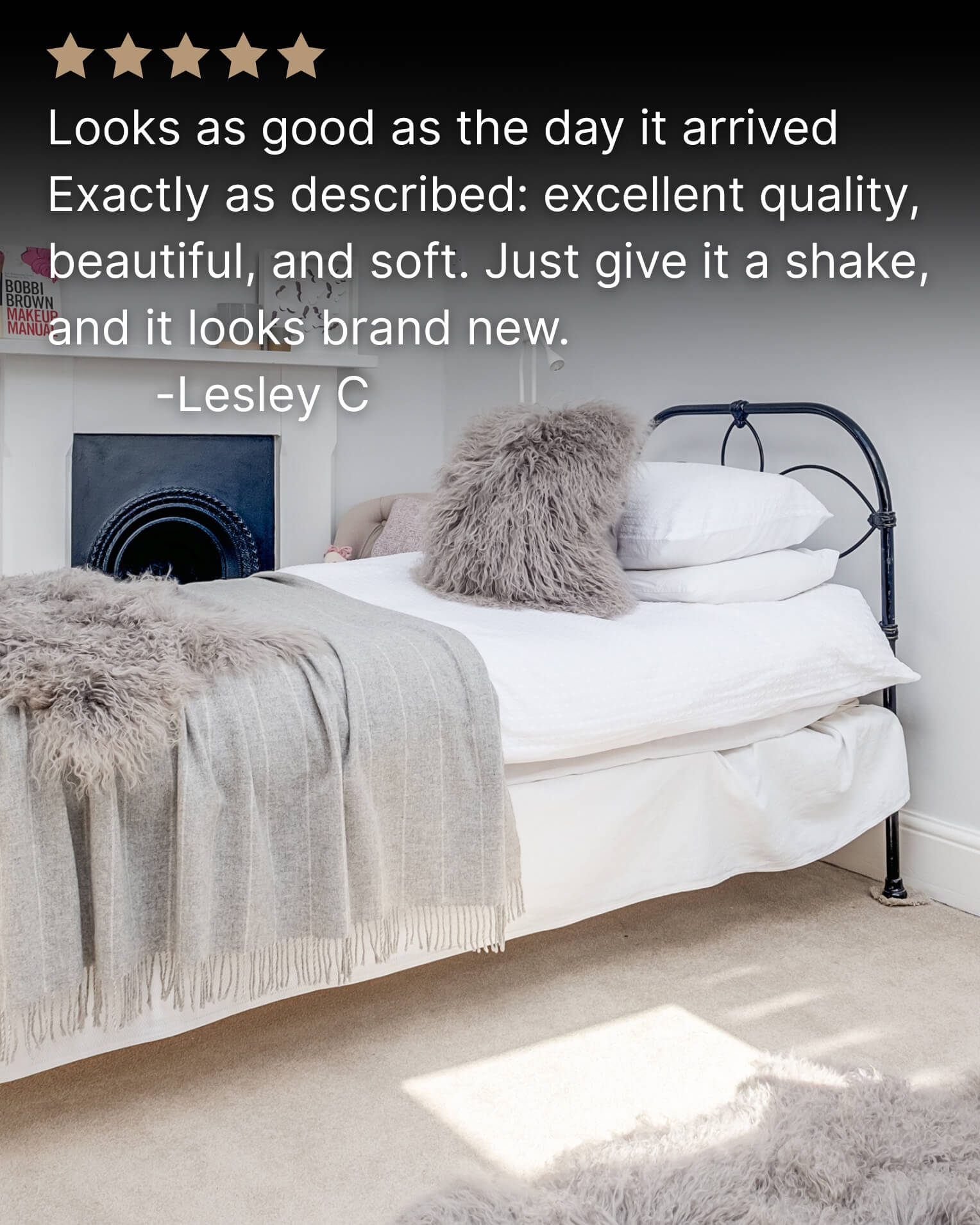 Grey mongolian sheepskin pillow on white bed with grey blanket