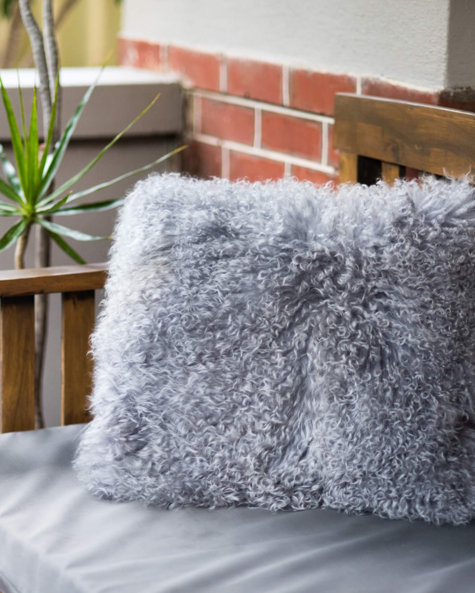 Grey mongolian sheepskin pillow close up on chair