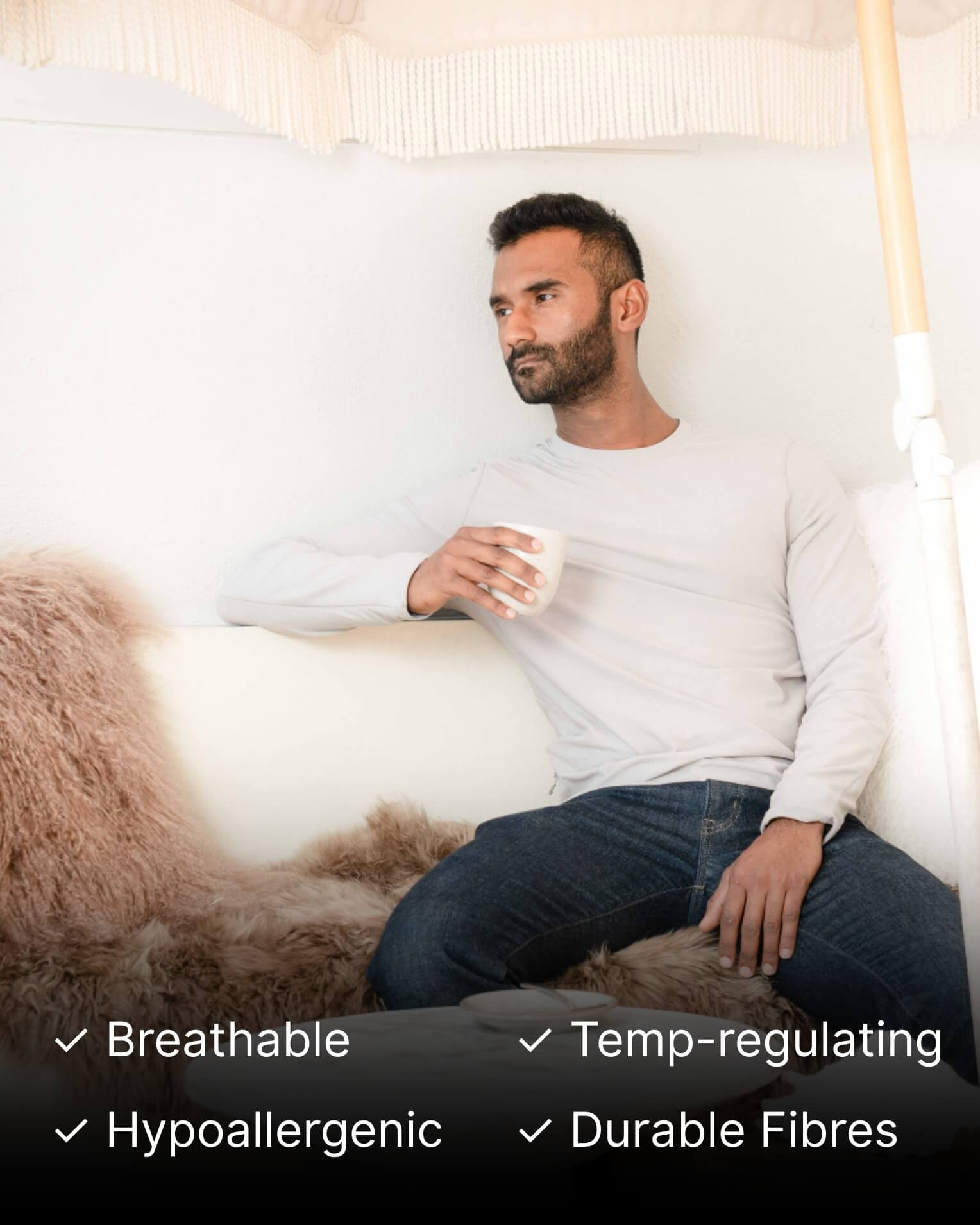 Man sitting on a couch holding a cup with Mocha Mongolian Sheepskin Rug