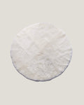 Product photos of a round ivory sheepskin playmat 