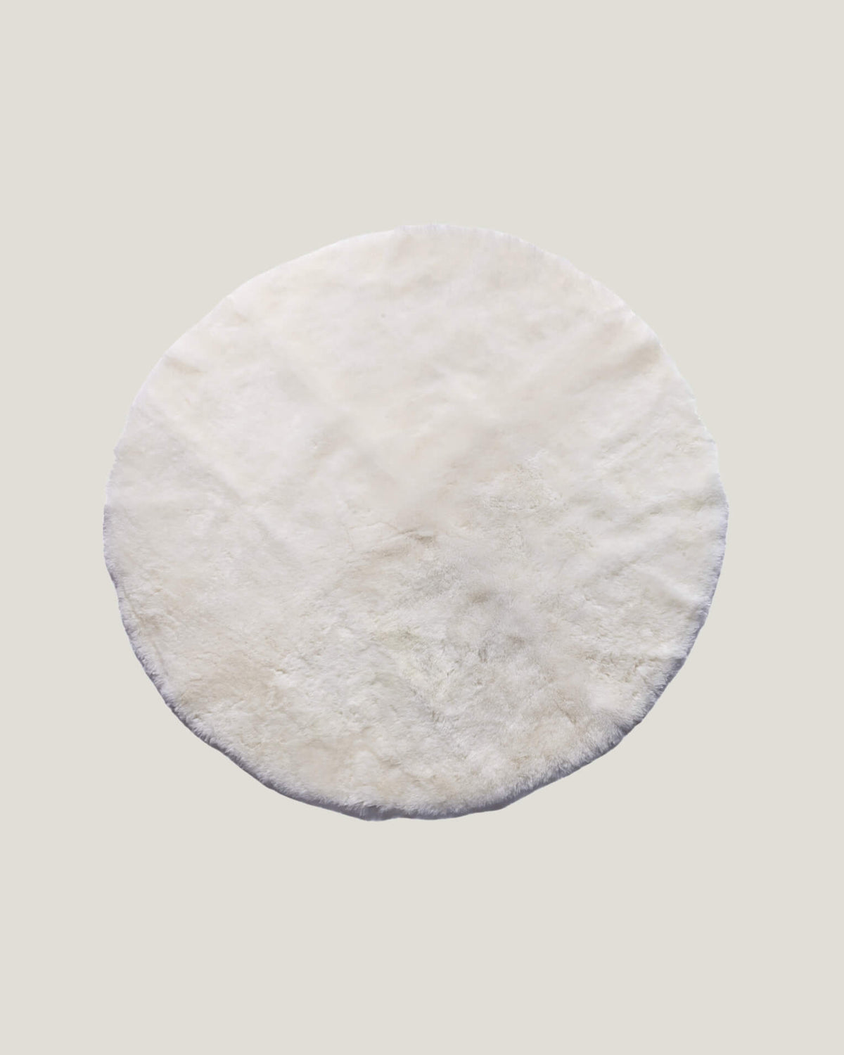Product photos of a round ivory sheepskin playmat 