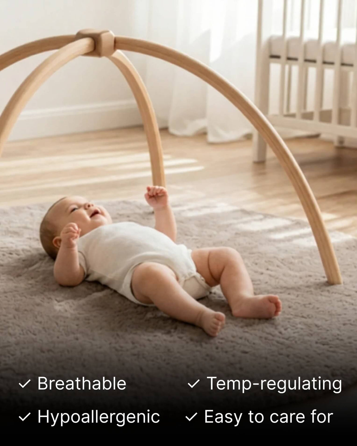 Baby under play mobile laying on round taupe sheepskin playmat 