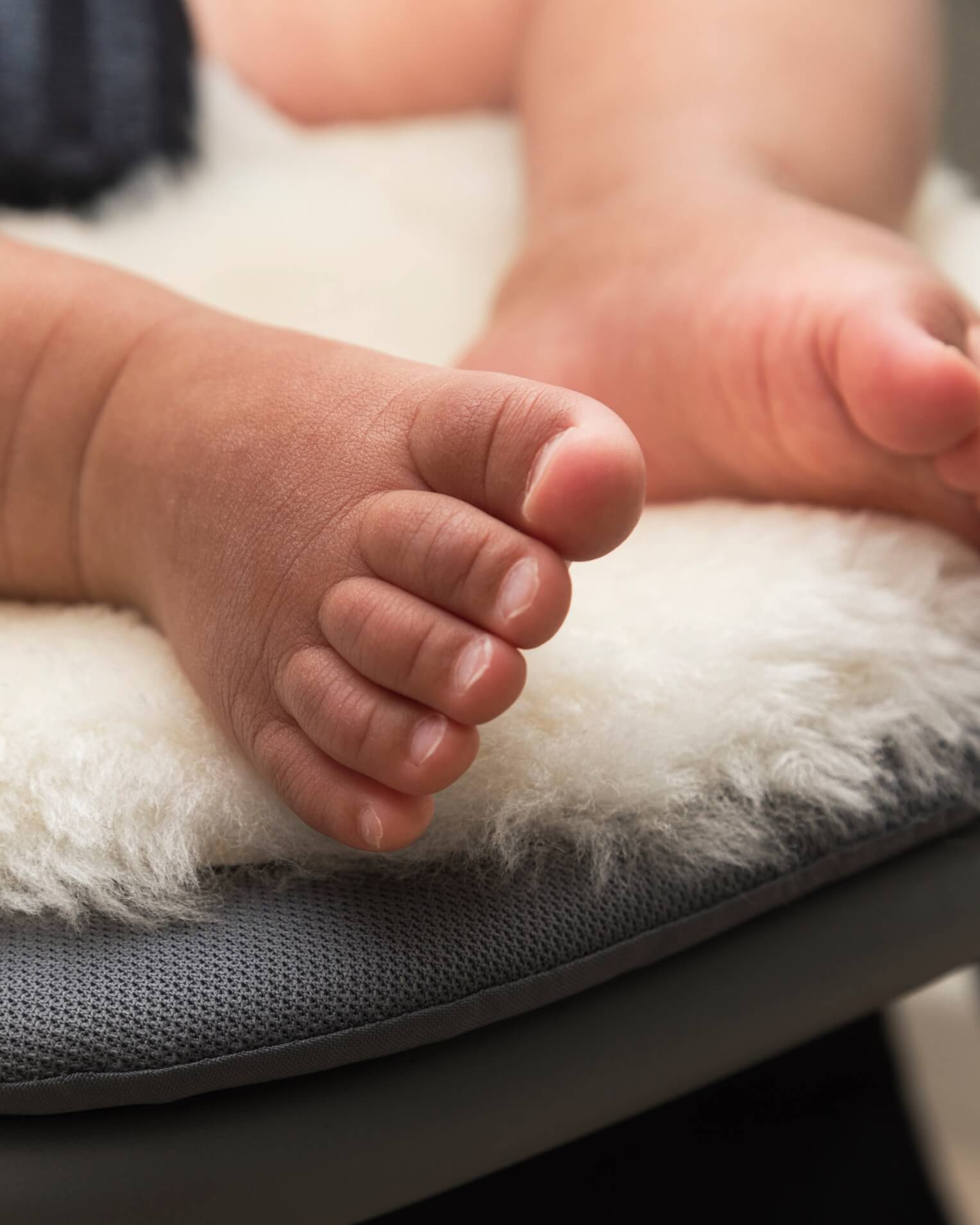 Close-up of a baby's feet on sheepskin pram liner
