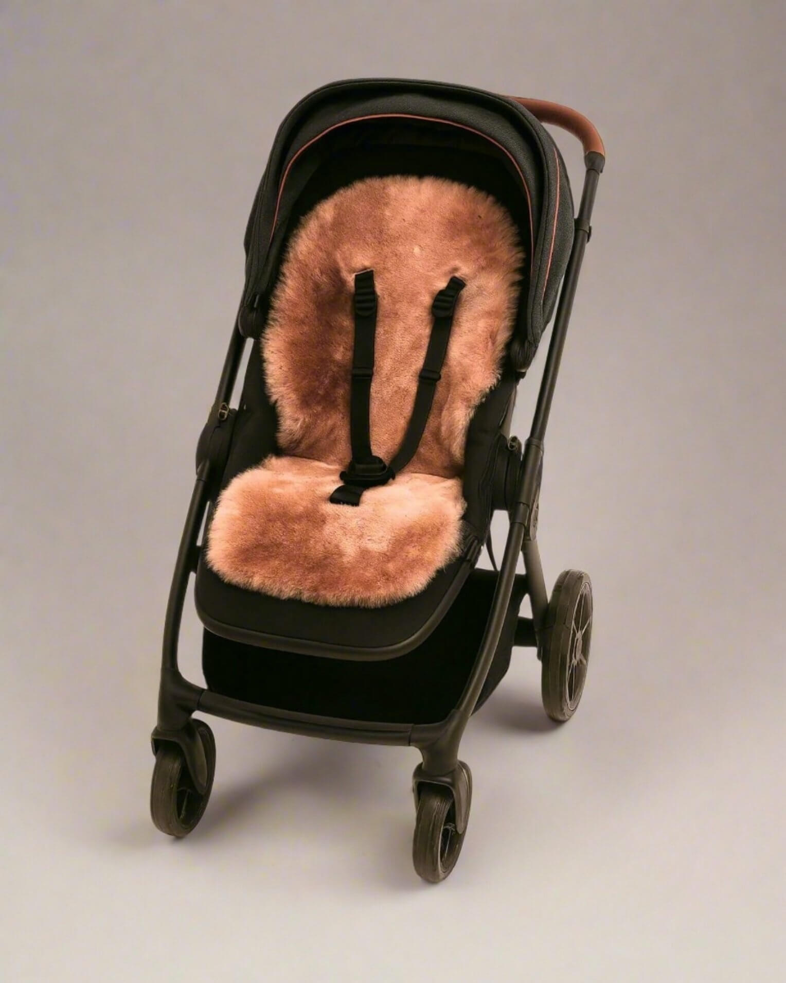 Black stroller with a rose gold sheepskin seat cover