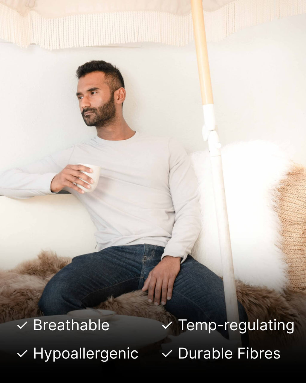 Man sitting on a couch holding a mug with Ivory Mongolian Sheepskin Rug